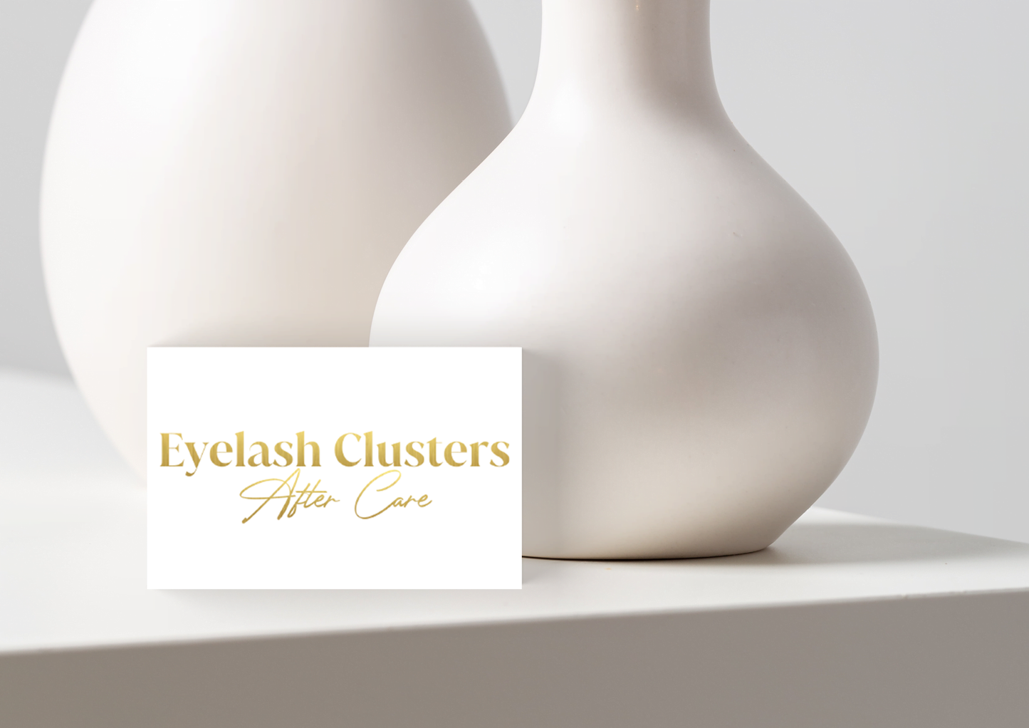 Allure Eyelash eyelash cluster aftercare cards with elegant gold text on white card beside white vases