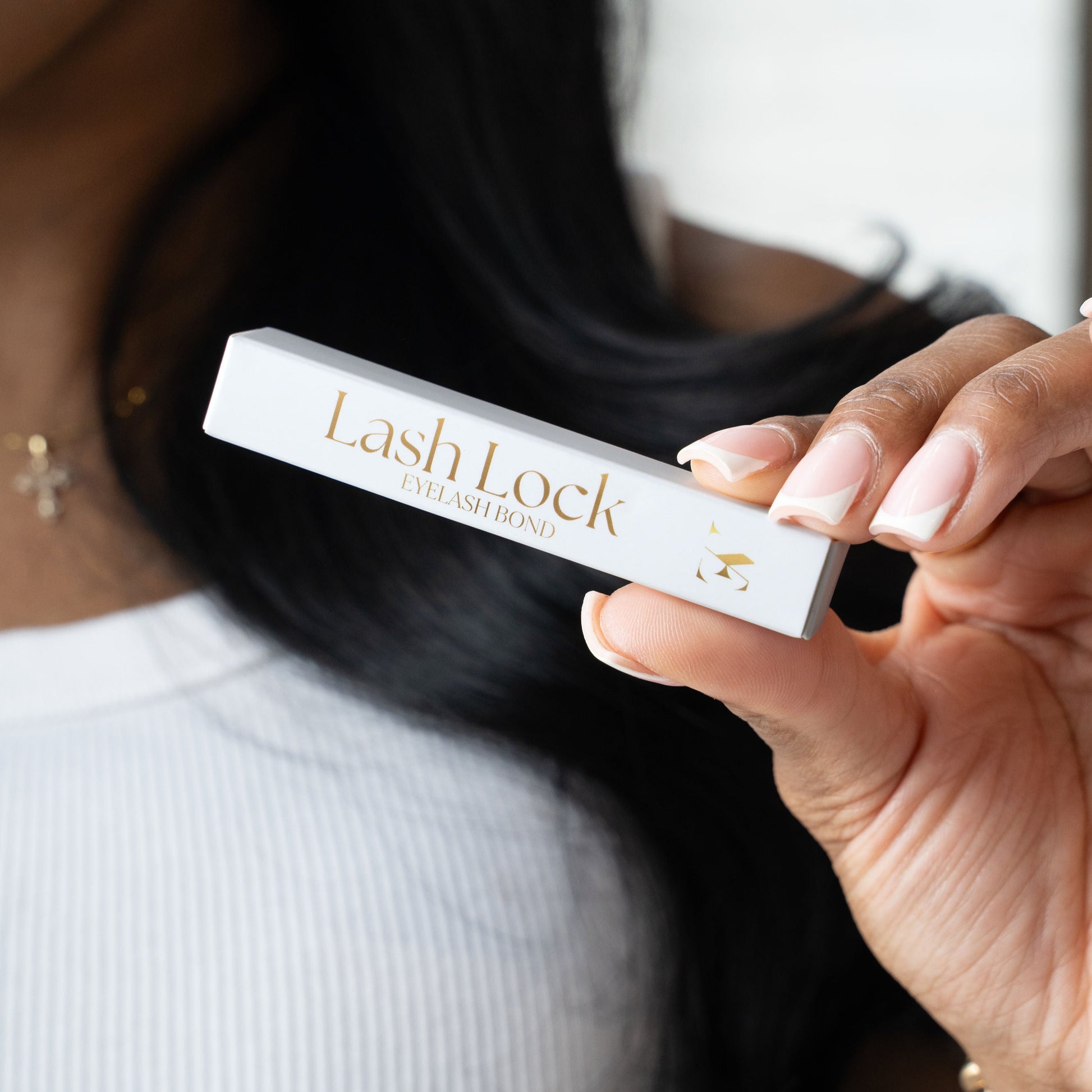 Hand holding Lash Lock eyelash bond packaging labeled as best eyelash glue for lash clusters